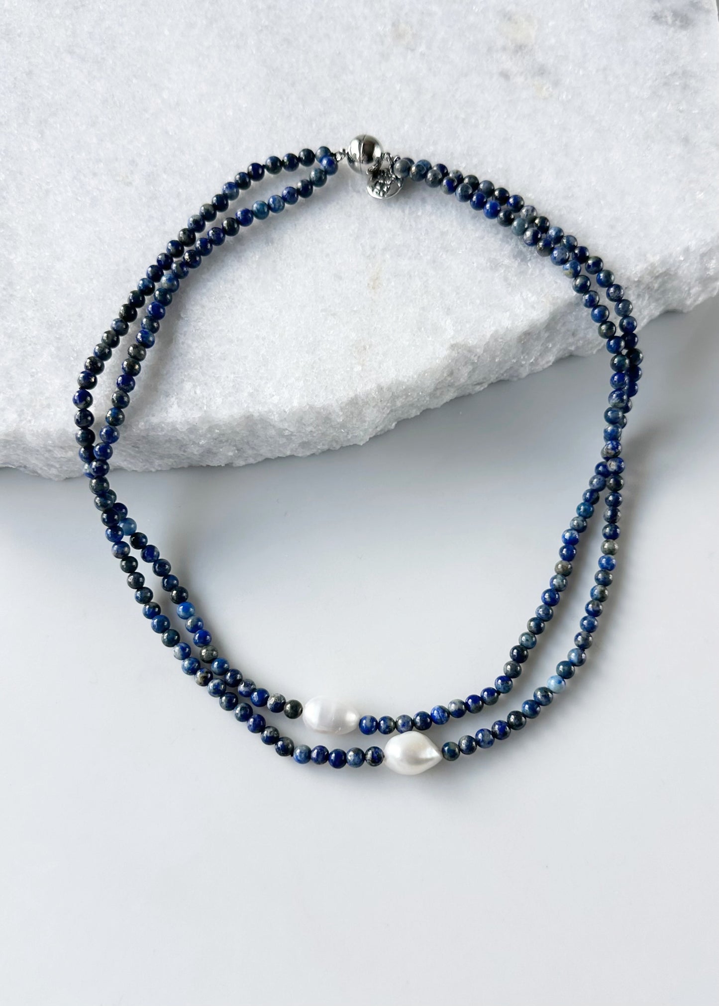 Beaded necklace with blue and white beads on a marble surface