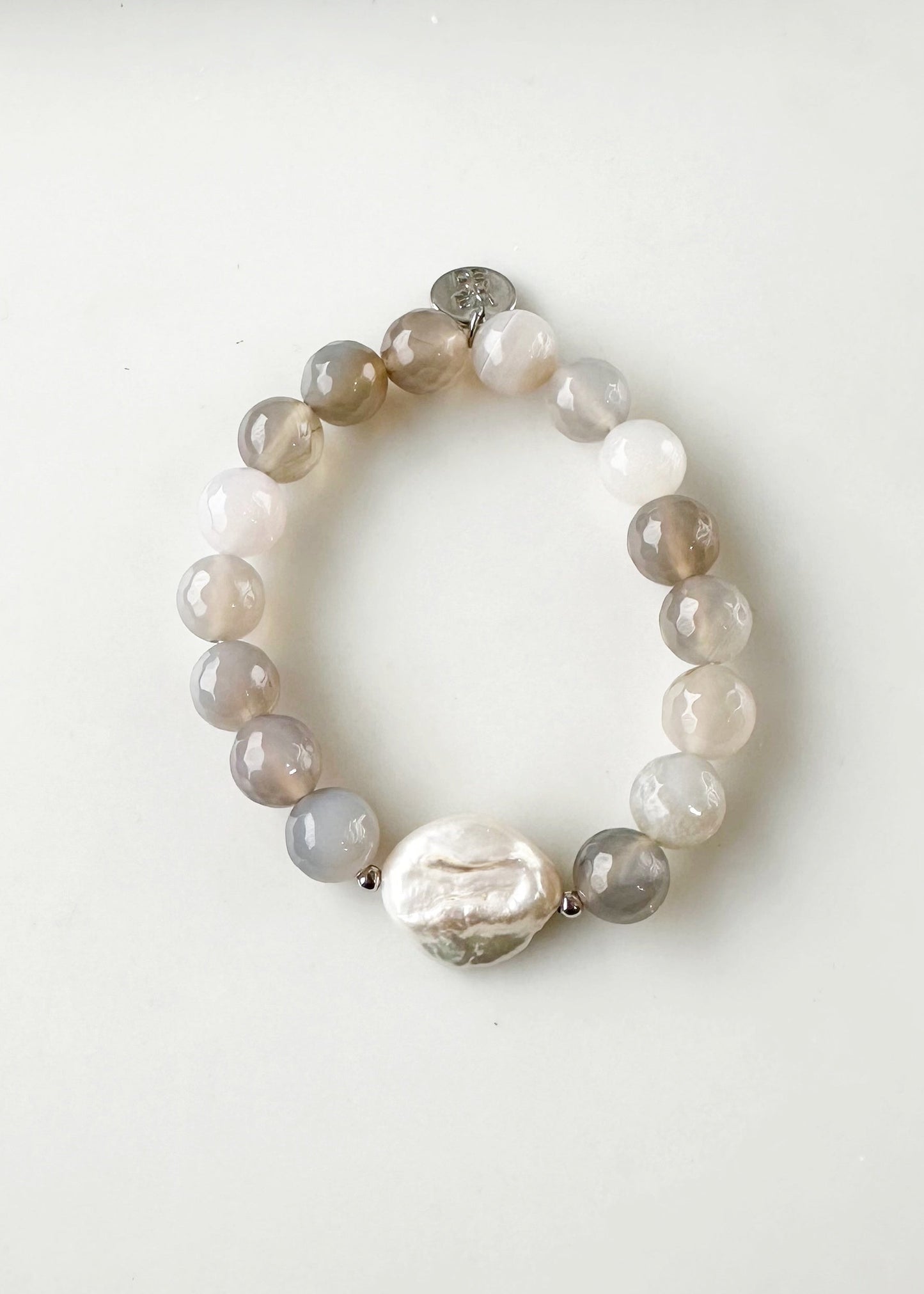 Freshwater White Coin Pearl Is Combined with 10mm Grey Agate and Glass with Metal Accents to form this Stretch Bracelet. A Subtle Yet Sophisticated Statement.