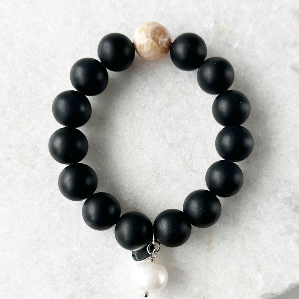 This 7” Stretch Bracelet Features a Large (14mm) Faceted Beige Agate Surrounded by Matte Black Agate with a Freshwater Pearl Dangle. Beautiful on it's own or added to your stack. Designed in Canada