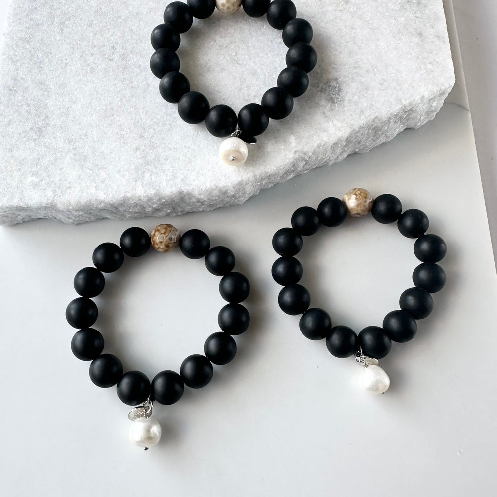 
                      
                        This 7” Stretch Bracelet Features a Large (14mm) Faceted Beige Agate Surrounded by Matte Black Agate with a Freshwater Pearl Dangle. Beautiful on it's own or added to your stack. Designed in Canada
                      
                    