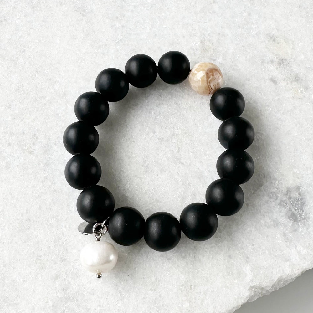 This 7” Stretch Bracelet Features a Large (14mm) Faceted Beige Agate Surrounded by Matte Black Agate with a Freshwater Pearl Dangle. Beautiful on it's own or added to your stack. Designed in Canada