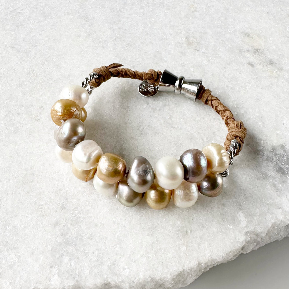 This 8” Bracelet has Two Knotted Strands of Large Freshwater Pearls with Braided Vegan Suede Accented with Silver Rings and a Magnetic Clasp. Designed in Canada