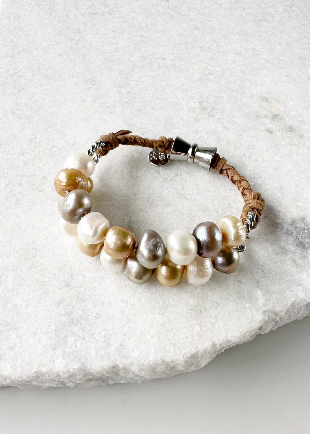 This 8” Bracelet has Two Knotted Strands of Large Freshwater Pearls with Braided Vegan Suede Accented with Silver Rings and a Magnetic Clasp. Designed in Canada