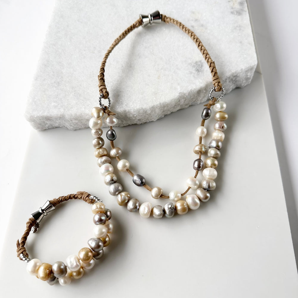 
                      
                        This 8” Bracelet has Two Knotted Strands of Large Freshwater Pearls with Braided Vegan Suede Accented with Silver Rings and a Magnetic Clasp. Designed in Canada
                      
                    