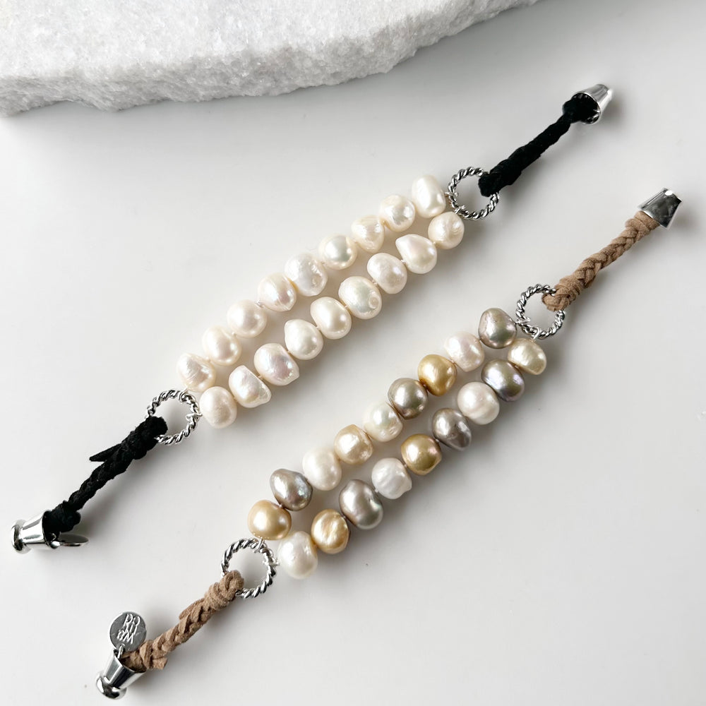 
                      
                        This 8” Bracelet has Two Knotted Strands of Large Freshwater Pearls with Braided Vegan Suede Accented with Silver Rings and a Magnetic Clasp. Designed in Canada
                      
                    
