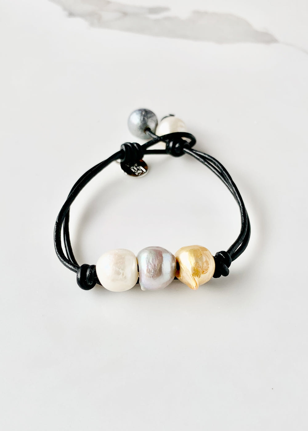 Black Leather Bracelet Highlighting Three Mixed-Color Baroque Freshwater Pearls with a Separate Pearl and Loop Closure. Can be worn Separately or Layered with other Bracelets.