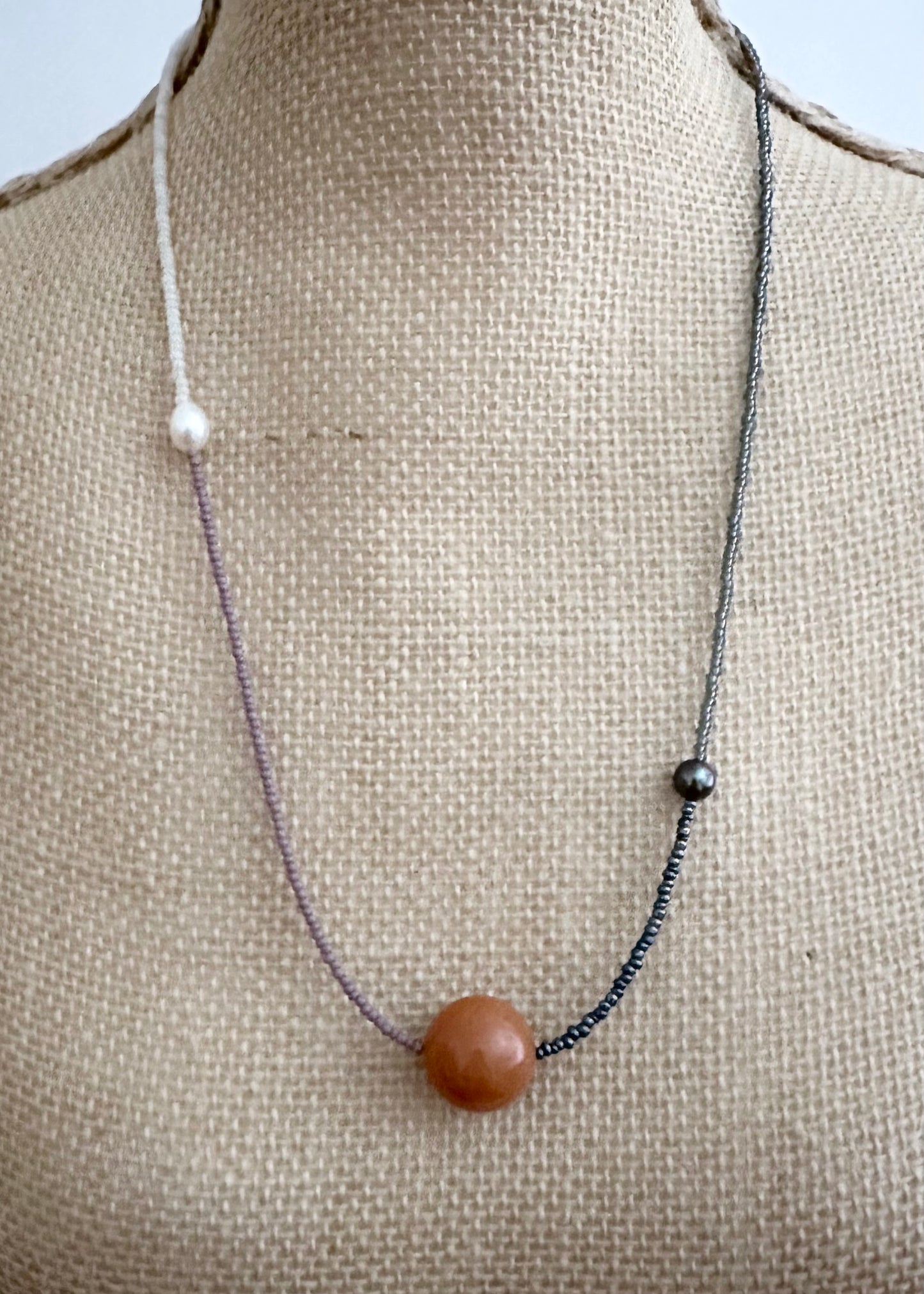 This 24.5” Necklace features Orange Aventurine (18mm), White and Black pearls, Glass Seed Beads in a Striking Asymmetrical Design. Designed and Made in Canada, to be wonderfully light and comfortable to wear, this Limited-Edition piece is completed with a Lobster Claw Clasp.