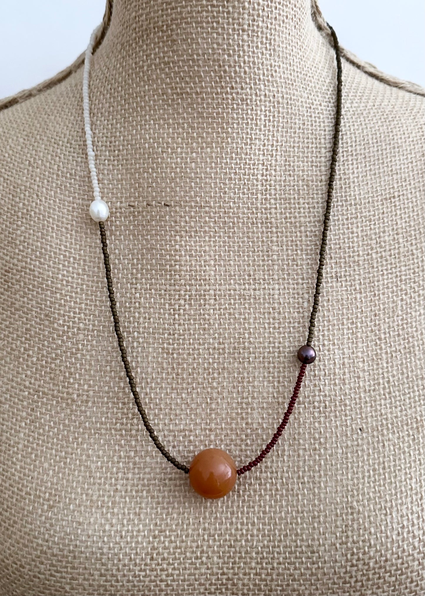 This 24.5” Necklace features Orange Aventurine (18mm), White and Black pearls, Glass Seed Beads in a Striking Asymmetrical Design. Designed and Made in Canada, to be wonderfully light and comfortable to wear, this Limited-Edition piece is completed with a Lobster Claw Clasp.