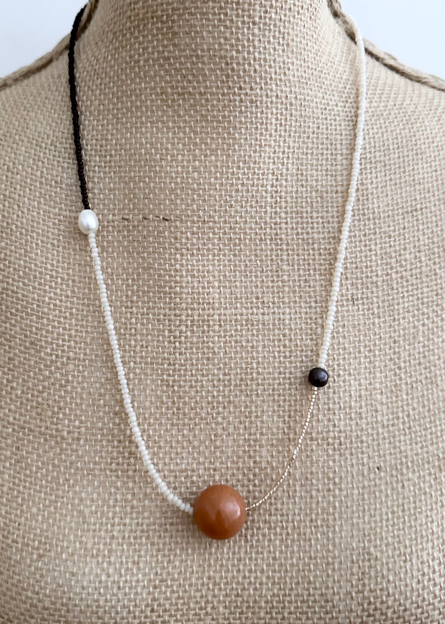 This 24.5” Necklace features Orange Aventurine (18mm), White and Black pearls, Glass Seed Beads in a Striking Asymmetrical Design. Designed and Made in Canada, to be wonderfully light and comfortable to wear, this Limited-Edition piece is completed with a Lobster Claw Clasp.