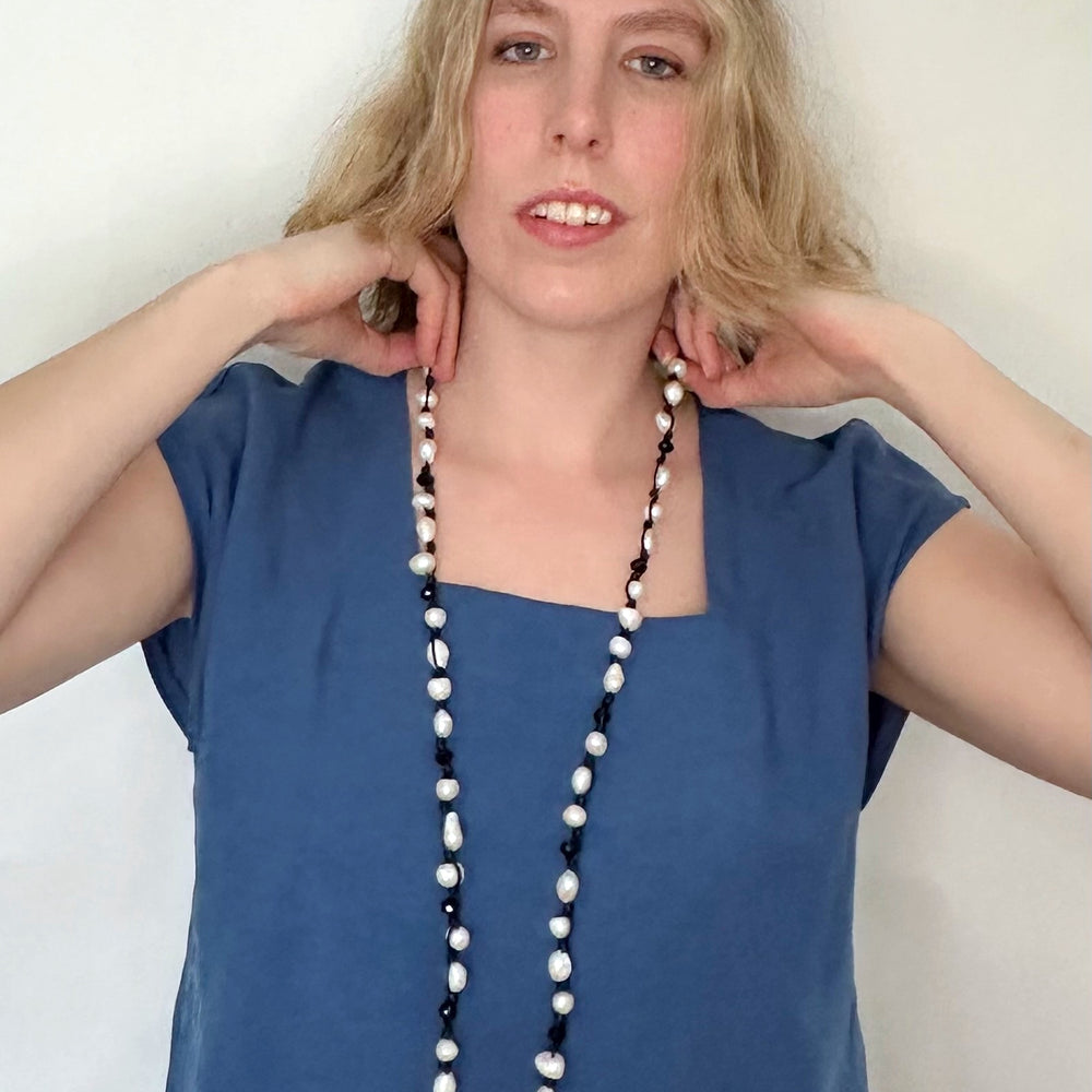 
                      
                        White Baroque Freshwater Pearls and Faceted Crystals Knotted on Black Cotton Cord on a 30” Necklace. On Model
                      
                    