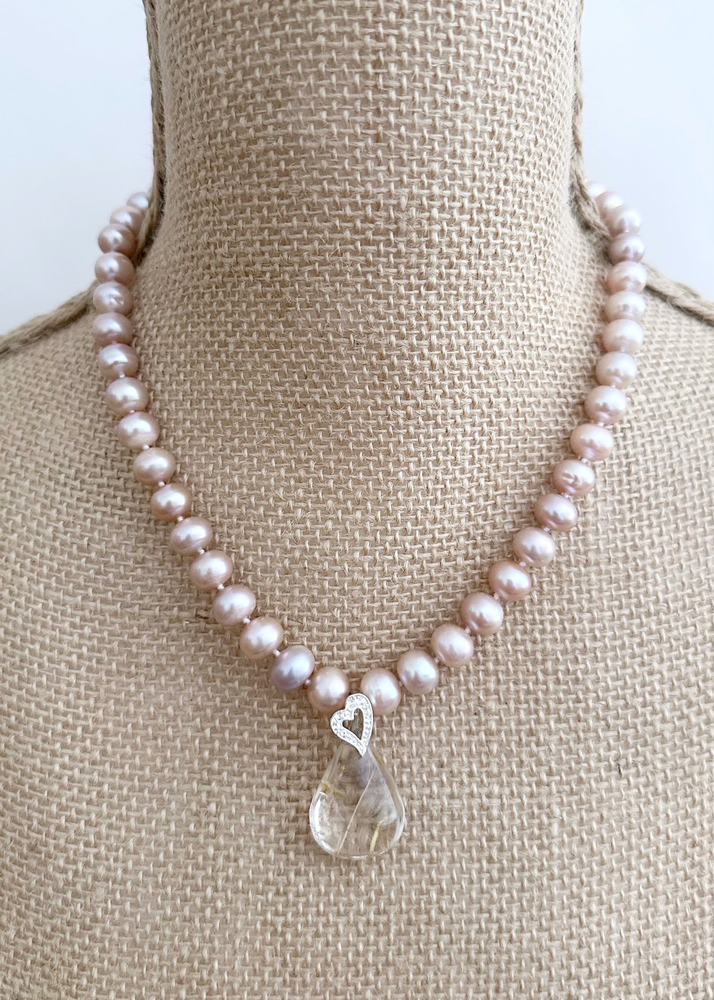 Designed and made in Canada, this Distinctive 18” Necklace Features Luminous Pink 9mm Pearls Paired with a Striking Rutilated Quartz Teardrop 1.25” Pendant Suspended from an Elegant Silver-Plated Heart-Shaped Bail and Completed with a Lobster Claw Clasp.