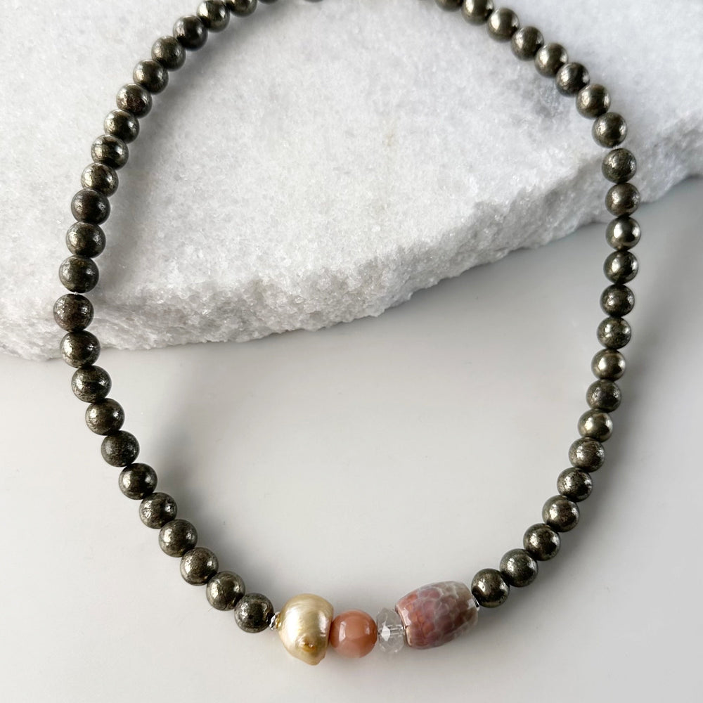 This 18.5” Limited Edition Necklace Boasts 8mm Pyrite, Gold Freshwater Pearl, Peach Moonstone, Clear Quartz, Brown-Scale Faceted Agate and Hematite.