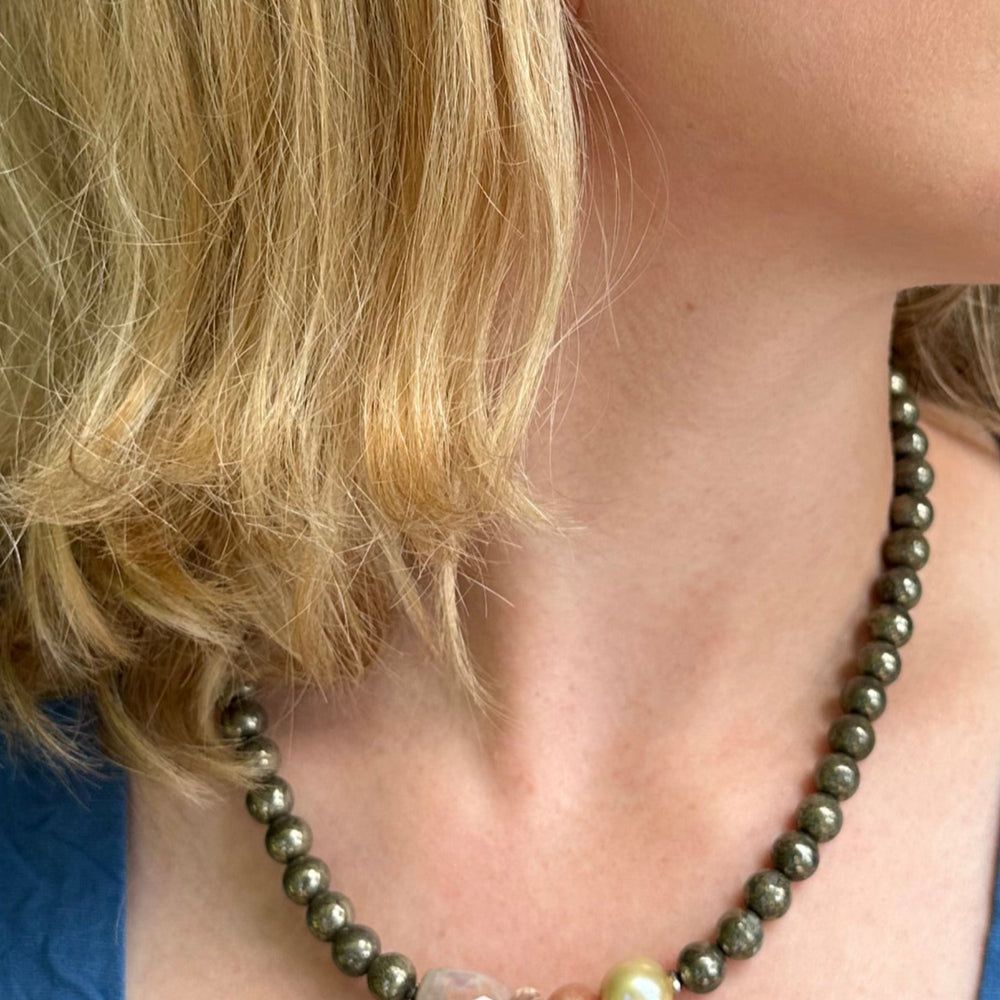 
                      
                        This 18.5” Limited Edition Necklace Boasts 8mm Pyrite, Gold Freshwater Pearl, Peach Moonstone, Clear Quartz, Brown-Scale Faceted Agate and Hematite. On Model
                      
                    