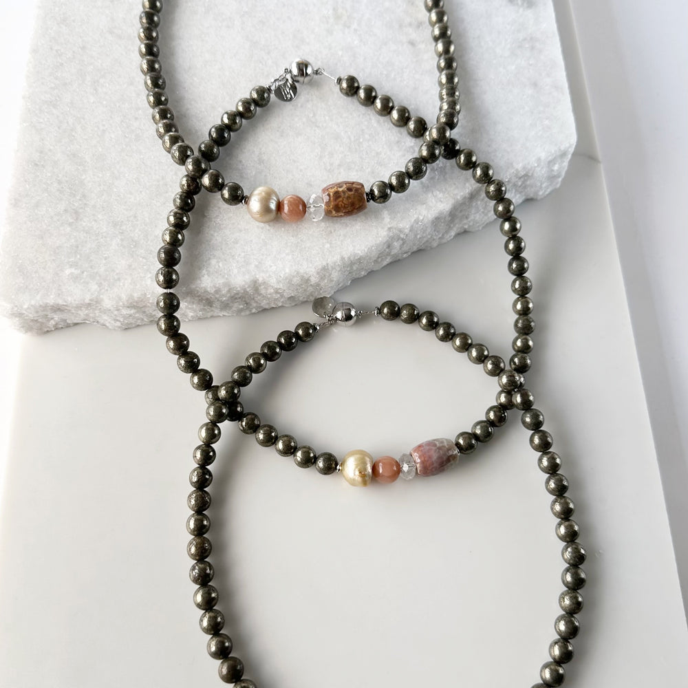 
                      
                        This 18.5” Limited Edition Necklace Boasts 8mm Pyrite, Gold Freshwater Pearl, Peach Moonstone, Clear Quartz, Brown-Scale Faceted Agate and Hematite. Three Shown
                      
                    