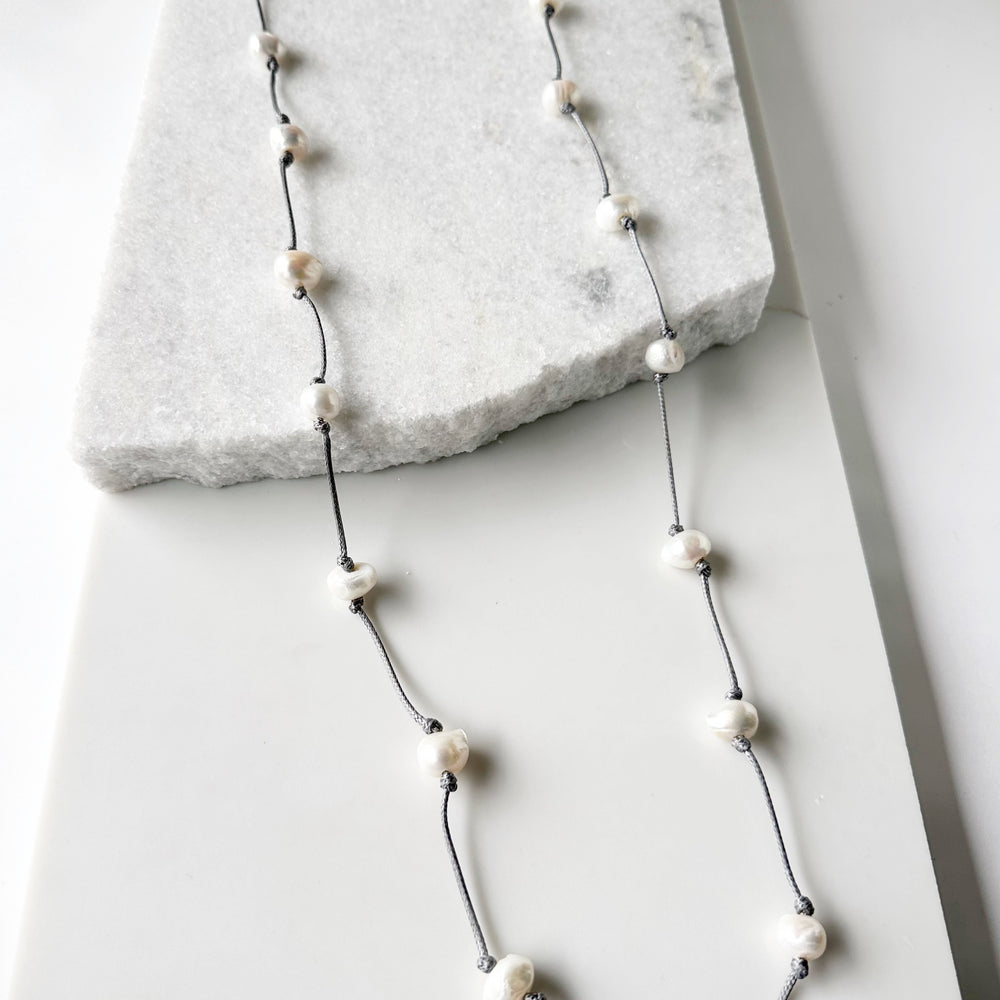 
                      
                        Lustrous White Freshwater Pearls  on Grey Cotton in this 21” Necklace.
                      
                    