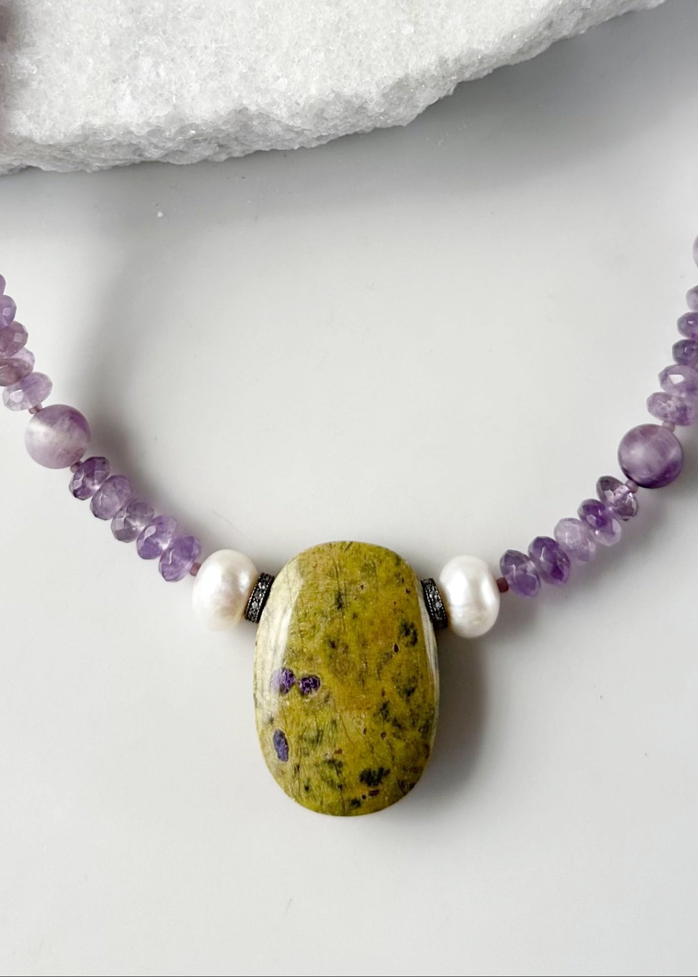 Designed and Made in Canada, this One-Of-A-Kind 20.5” Necklace features a large Stichtite Pendant, a Stunning Natural Stone known for its Purple and Green hues. Paired with Lustrous Freshwater Pearls, Faceted Amethyst and Matte Round Amethyst this piece combines elegance with organic charm.  This piece is finished with a Sterling Silver Lobster Claw Clasp.