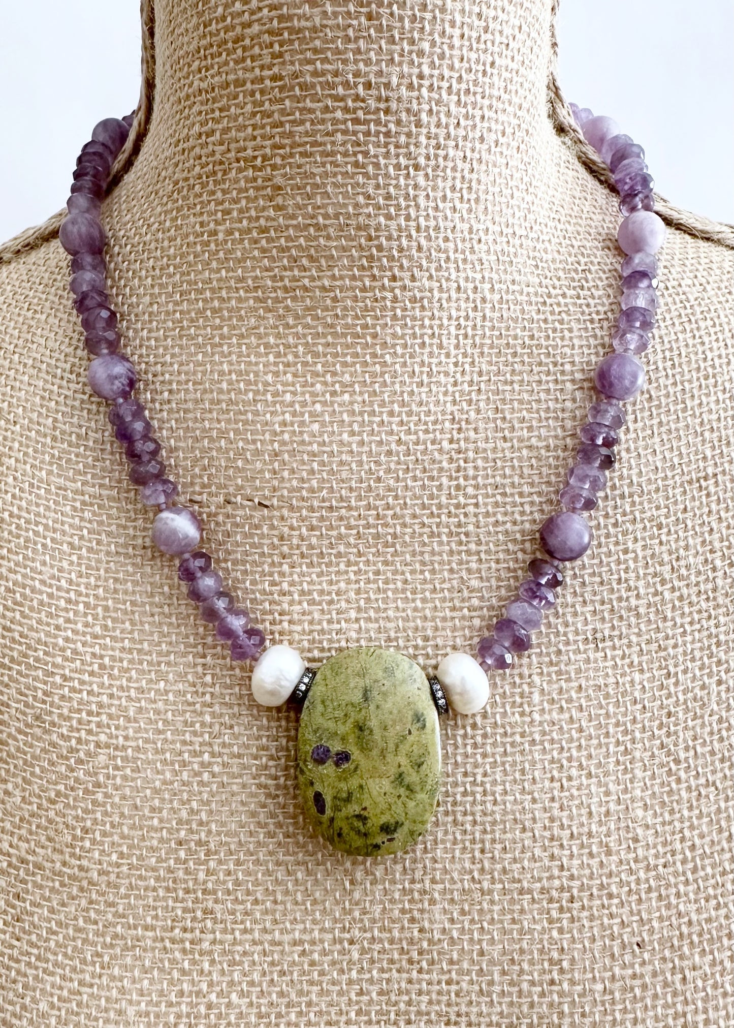 Designed and Made in Canada, this One-Of-A-Kind 20.5” Necklace features a large Stichtite Pendant, a Stunning Natural Stone known for its Purple and Green hues. Paired with Lustrous Freshwater Pearls, Faceted Amethyst and Matte Round Amethyst this piece combines elegance with organic charm.  This piece is finished with a Sterling Silver Lobster Claw Clasp.