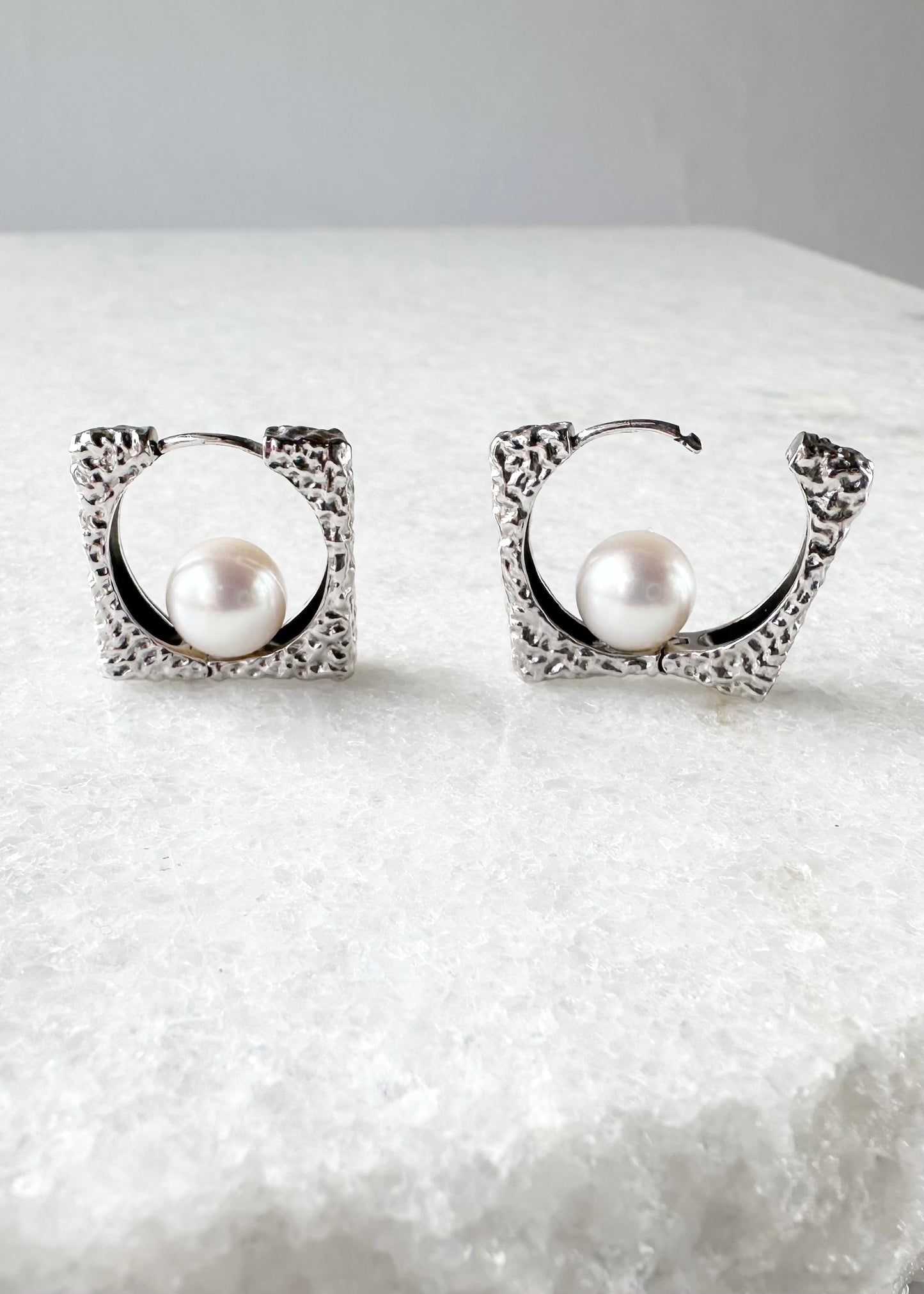 These Unique Earrings have Lustrous A+ White 8mm Freshwater Pearls Nestled in Hammered Silver Squares for a Modern Look. The Hinged Closure keeps everything Secure and Comfortable.  This piece is Completed with Sterling Silver Hammered Hoops.