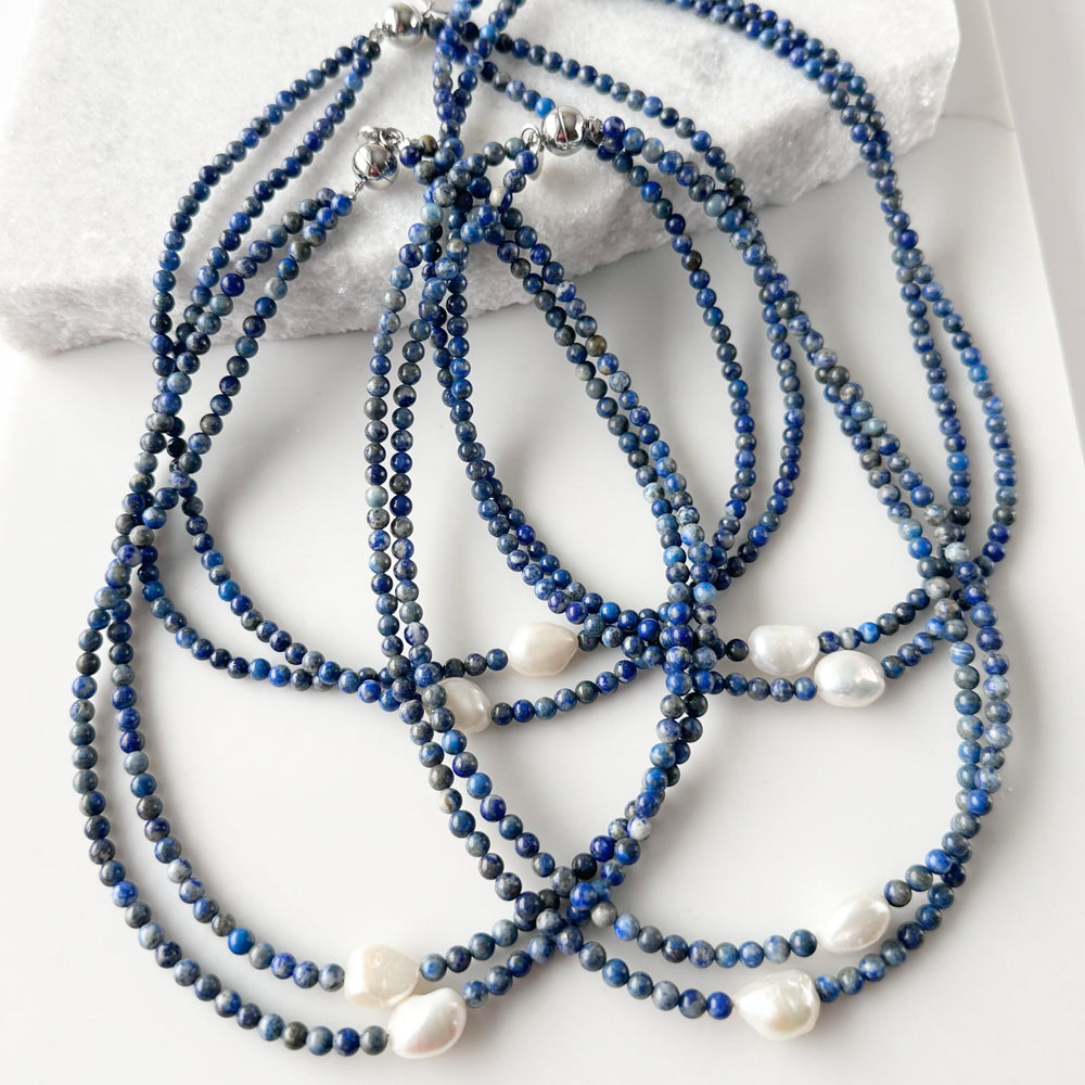 
                      
                        Two Lustrous White Baroque Freshwater Pearls are Highlighted and Offset on an 18” Necklace of Two Strands with 4mm Blue or Black Semi-Precious Stones Finished with a Strong Secure Magnetic Clasp for Easy Wear. Four Shown
                      
                    