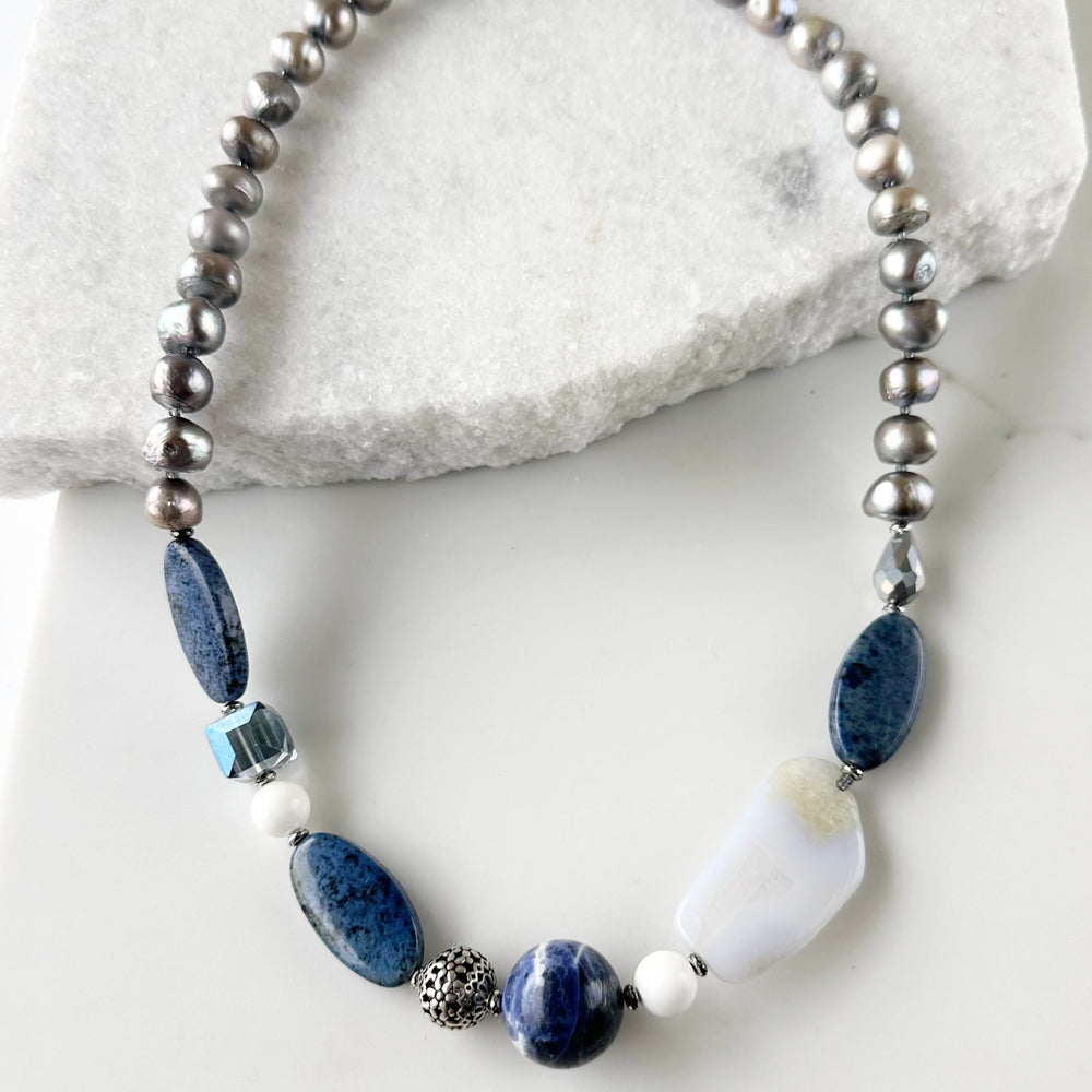 This Unique 23” Necklace Combines a Captivating Blend of Sodalite, Blue Lace Agate, Dumortierite, Silver, Crystal, Silver Freshwater Pearls and Finished with a Magnetic Clasp, Creating a Truly Distinctive Piece. Designed and made in Canada