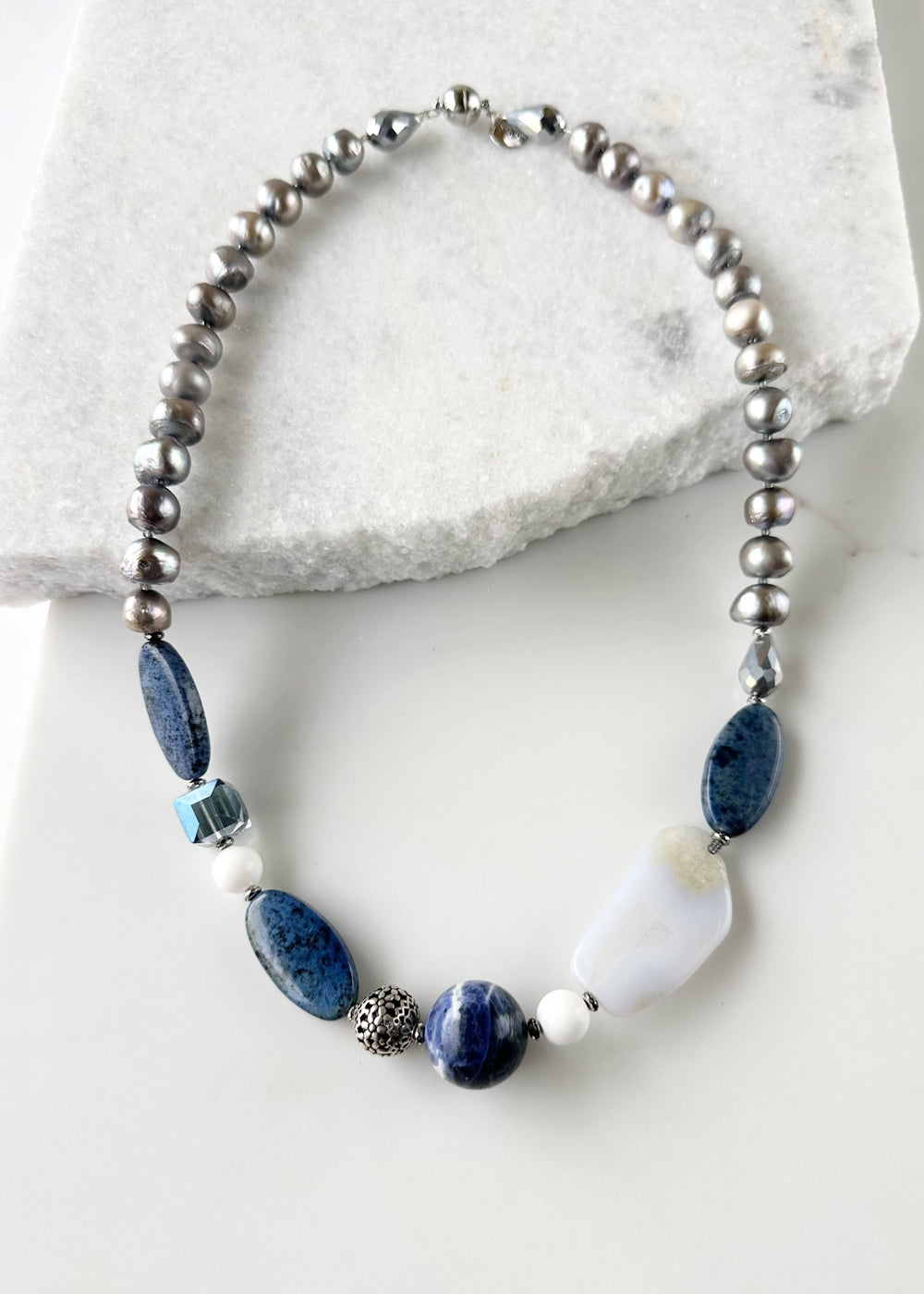 This Unique 23” Necklace Combines a Captivating Blend of Sodalite, Blue Lace Agate, Dumortierite, Silver, Crystal, Silver Freshwater Pearls and Finished with a Magnetic Clasp, Creating a Truly Distinctive Piece. Designed and made in Canada