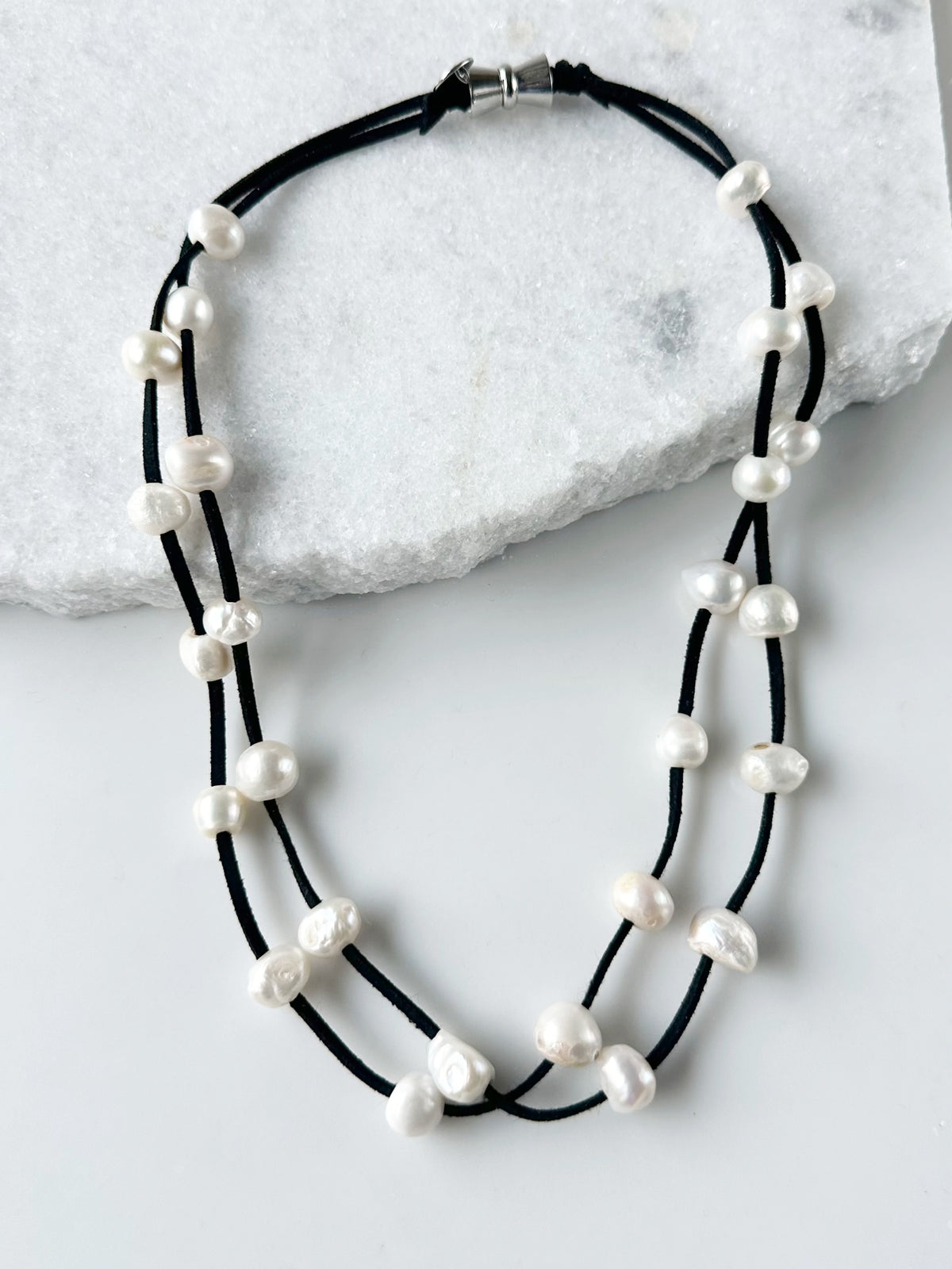 Designed in Canada, the 21.5” Suki Necklace has 2 strands of Large Organic Freshwater Pearls Floating on Vegan Suede (six Colour Options). It's Finished with a Magnetic Clasp for Easy Wear.