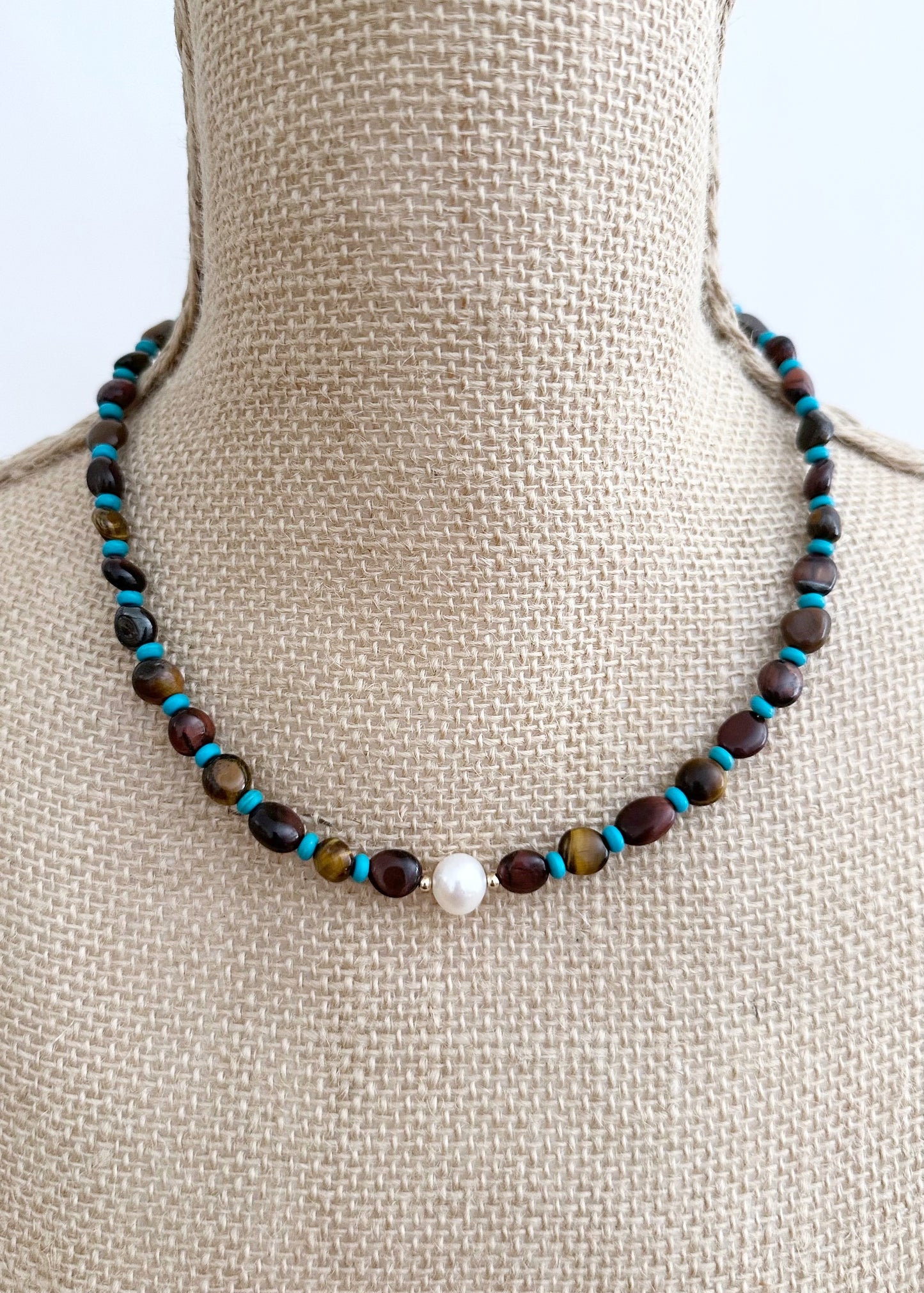 Designed and Made in Canada, this One-Of-A-Kind 18” Necklace features a Beautiful White Pearl Surrounded by Blue Tibetan Turquoise, Gold and Red Tiger's Eye, and Tiny Gold Accents.  This Piece is Finished with a Gold-filled Lobster Claw Clasp.