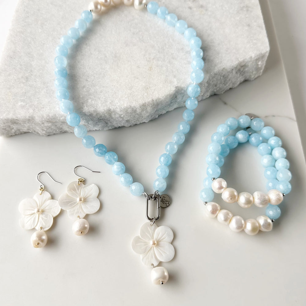 
                      
                        Five Large White Baroque Freshwater Pearls Accompanied by Light Blue Semi-Precious Stones (10 mm) with Silver accents in this 7” Stretch Bracelet. Matching Flora Necklace and Farrah Earrings also shown.
                      
                    