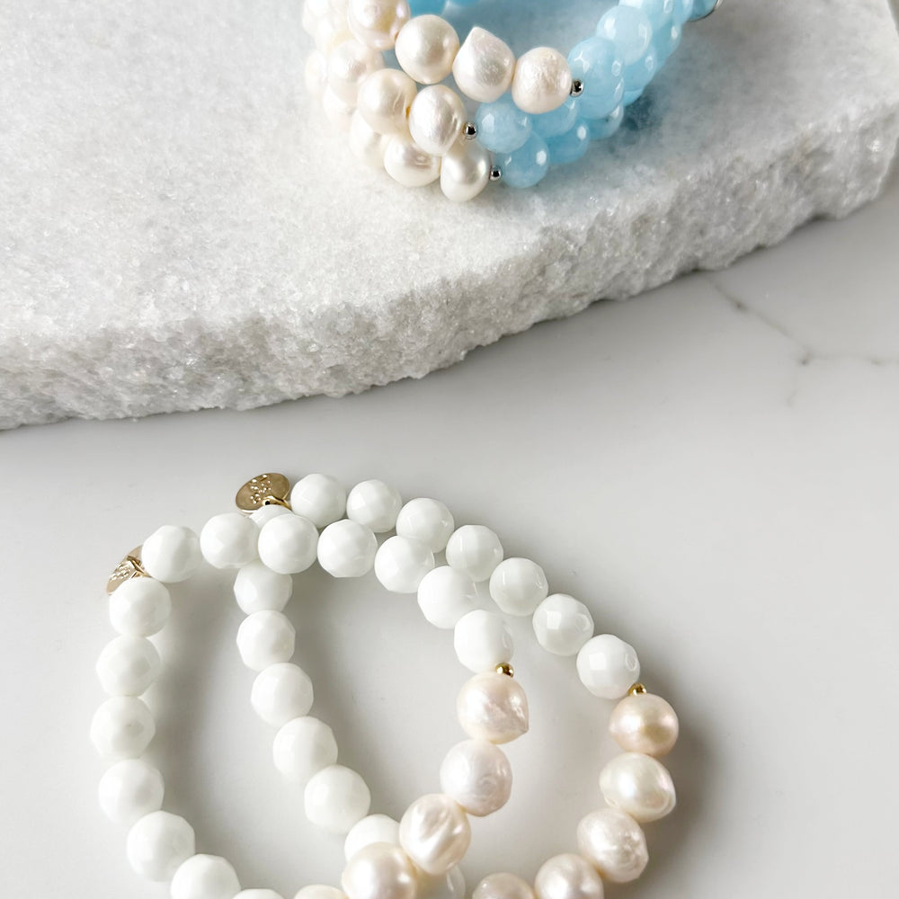 
                      
                        Five Large White Baroque Freshwater Pearls Accompanied by White or Light Blue Semi-Precious Stones (10 mm) with Silver or Gold accents in this 7” Stretch Bracelet. Both Shown
                      
                    