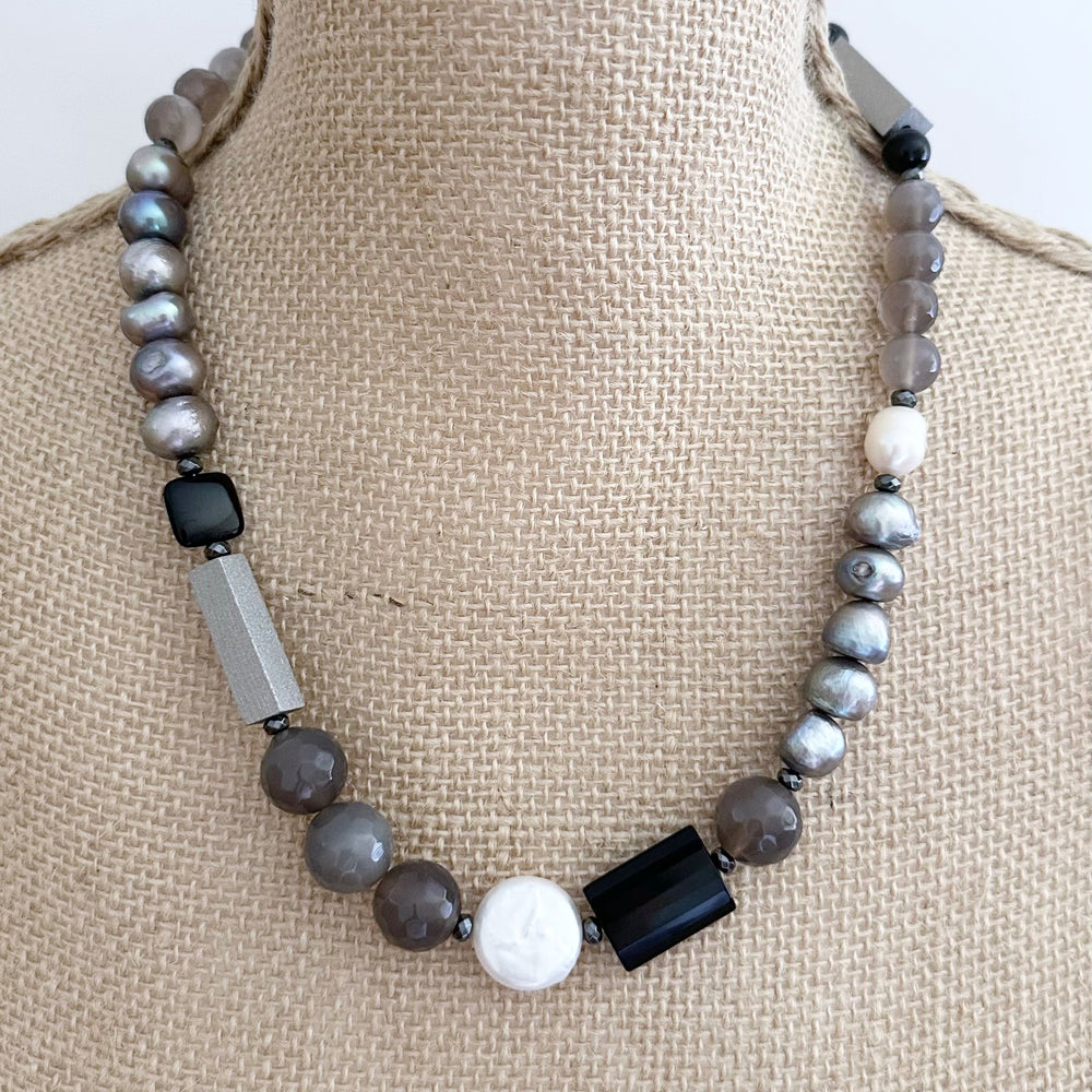 This Limited Edition 21” Necklace, Features Silver and White Freshwater Pearls Complemented by Striking Black Onyx, Silver Wood, Hematite and Soothing Grey Agate. A Magnetic Clasp offers simple, reliable attachment. This unique blend offers a bold yet elegant necklace that enhances any outfit and highlights your distinctive style. Designed and made in Canada