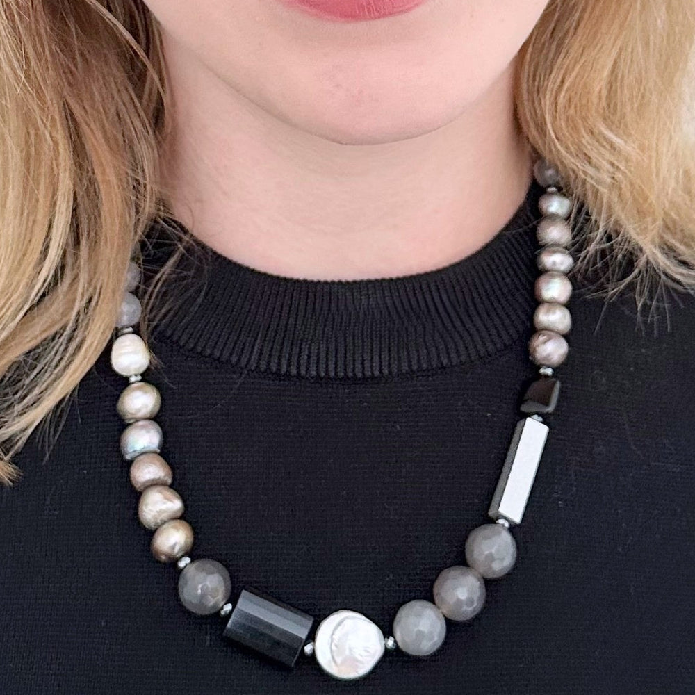 This Limited Edition 21” Necklace, Features Silver and White Freshwater Pearls Complemented by Striking Black Onyx, Silver Wood, Hematite and Soothing Grey Agate. A Magnetic Clasp offers simple, reliable attachment. This unique blend offers a bold yet elegant necklace that enhances any outfit and highlights your distinctive style. Designed and made in Canada