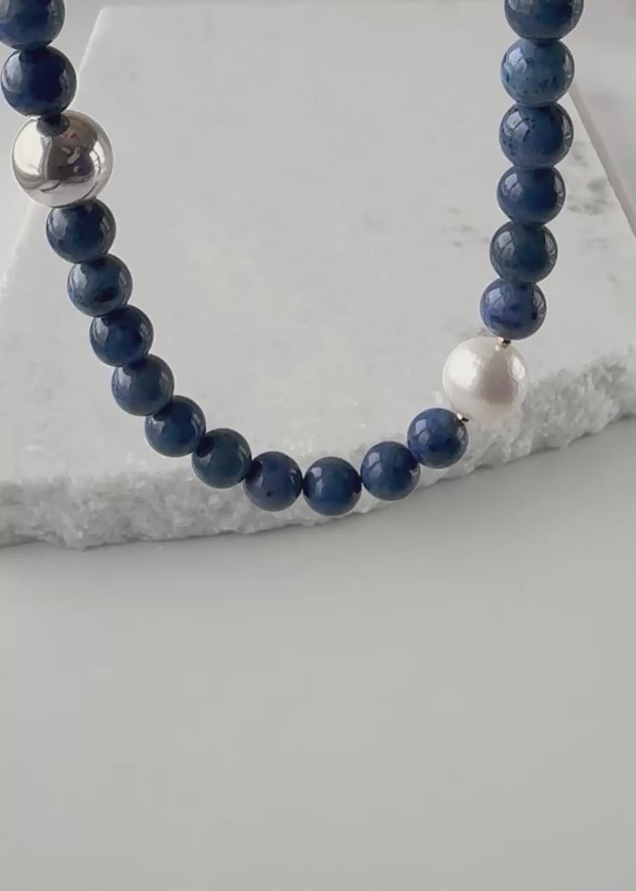 Designed and made in Canada, this One-Of-A-Kind 21” Necklace Features Beautiful Blue Dumortierite with a Large White Pearl, tiny Gold Accents and large Sterling Silver Bead. Simple, modern and stunning, the piece is completed with a Sterling Silver Lobster Claw Clasp.