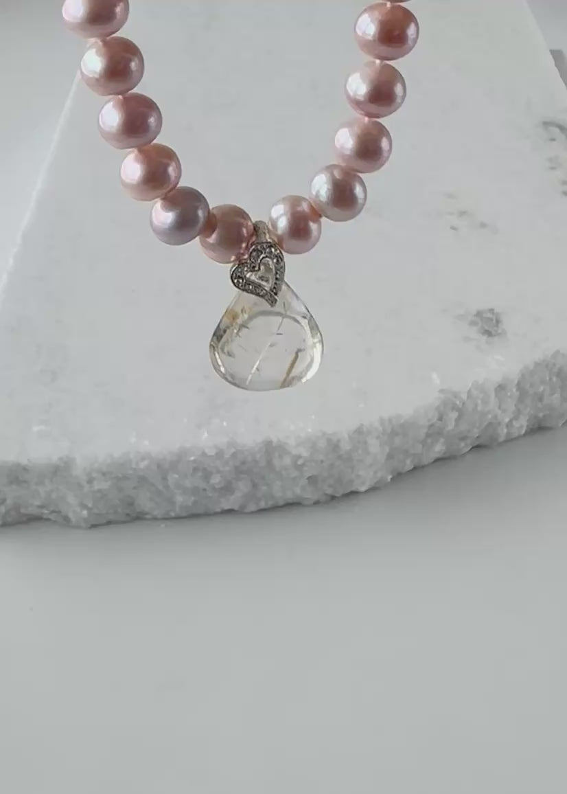 Designed and made in Canada, this Distinctive 18” Necklace Features Luminous Pink 9mm Pearls Paired with a Striking Rutilated Quartz Teardrop 1.25” Pendant Suspended from an Elegant Silver-Plated Heart-Shaped Bail and Completed with a Lobster Claw Clasp.