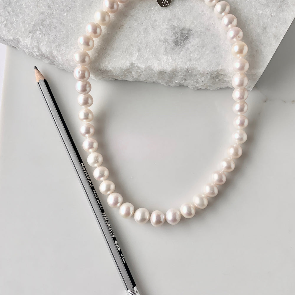 
                      
                        Large (11-12mm) Lustrous White Freshwater Pearl Necklace with Bean Clasp for Easy Wear. Alongside Pencil for Scale.
                      
                    