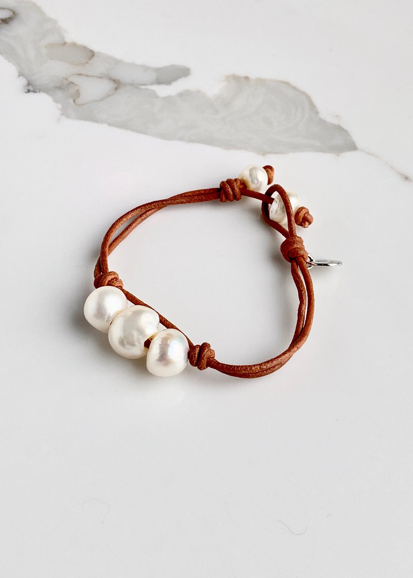 Tan Leather Bracelet Highlighting Three White Baroque Freshwater Pearls with a Separate Pearl and Loop Closure. Can be worn Separately or Layered with other Bracelets.
